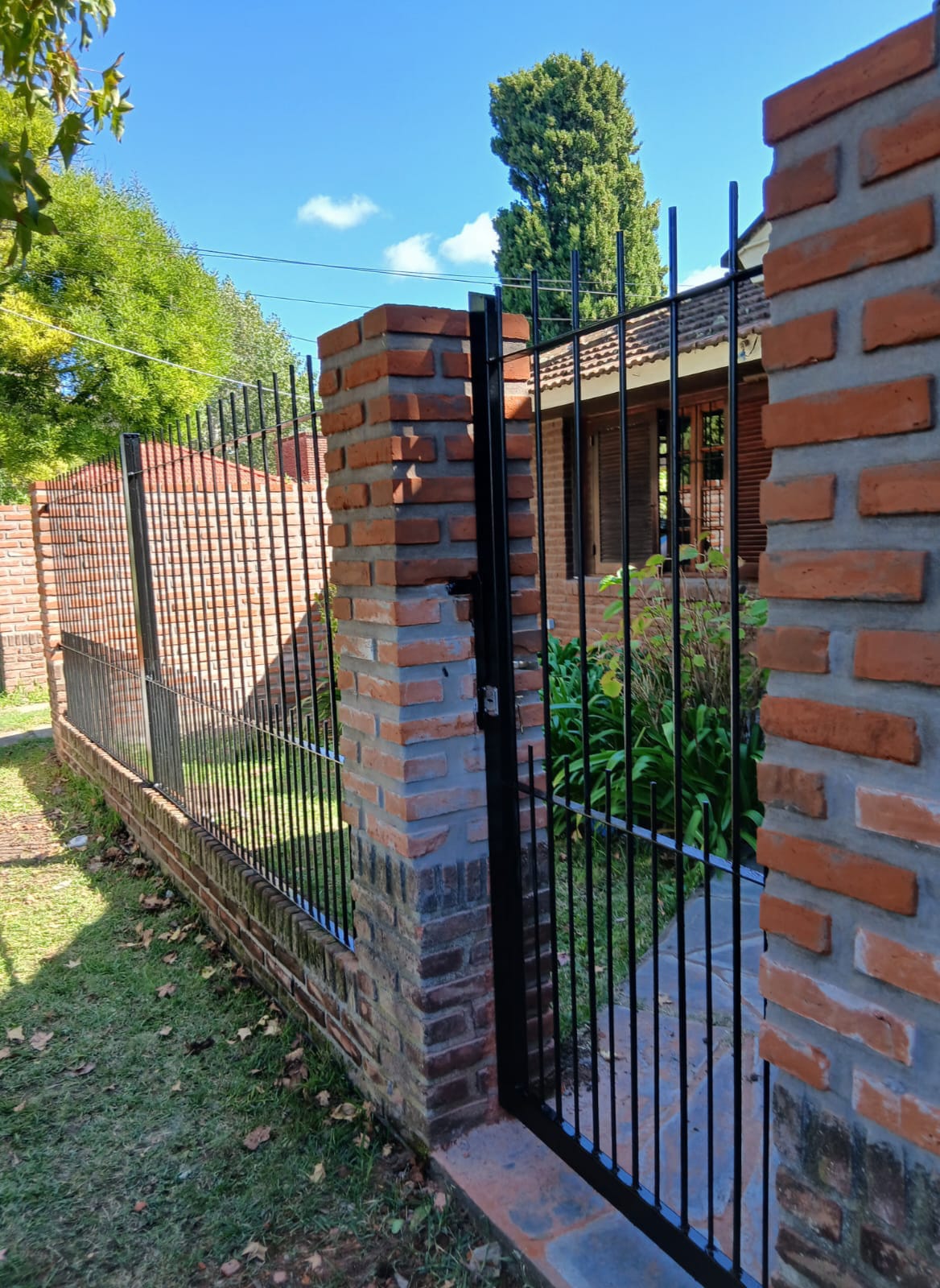 Reja negra de jardín con puerta batiente y pilares de ladrillo — Mar del Plata